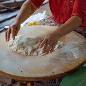 Hands of Turkish cook preparing potato and cheese gozleme on wooden table. Traditional stuffed